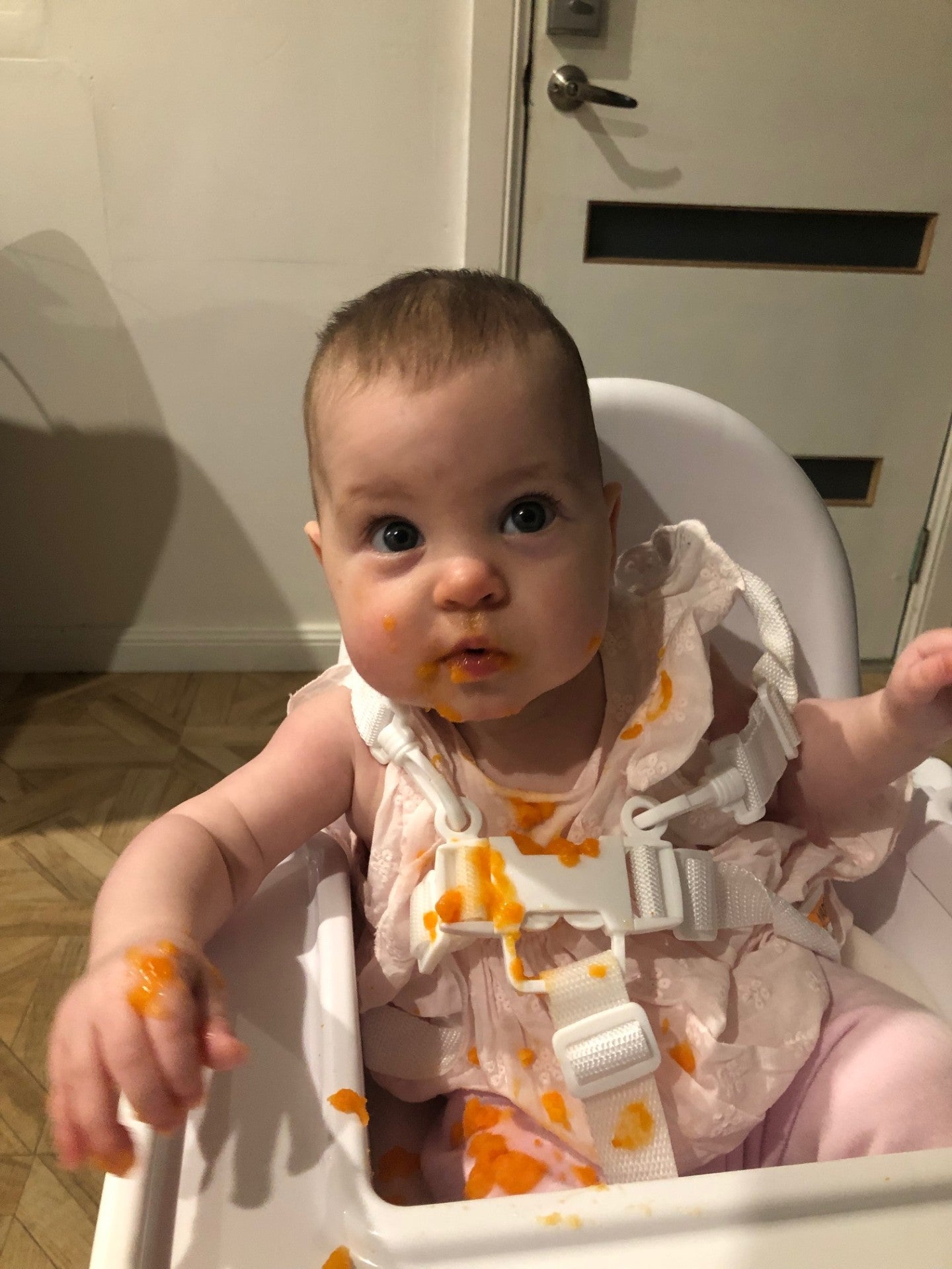 baby girl with messy pumpkin puree in high chair all over high chair straps