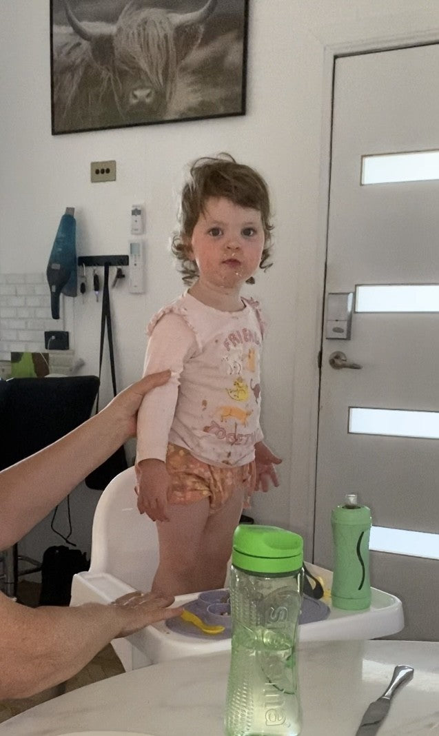 Toddler standing in high chair at dinner time with no harness on
